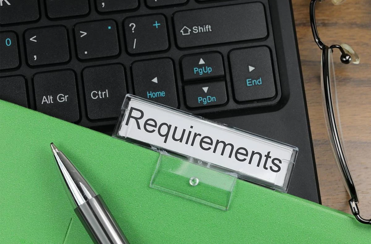 A folder with the label "requirements" and a pen sit on top of a keyboard