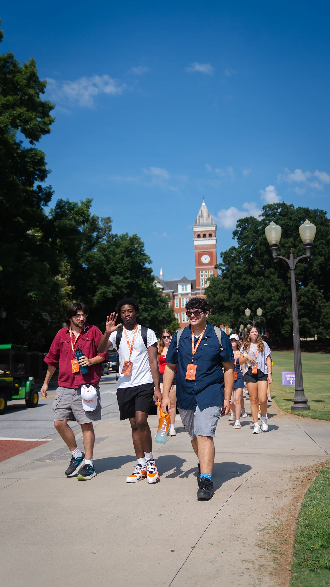 A group of students is walking on a sunny day with a clock tower in the background.