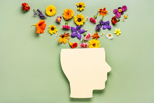 Paper cutout silhouette of a person's profile with top cut off and flowers appearing to come out of the head